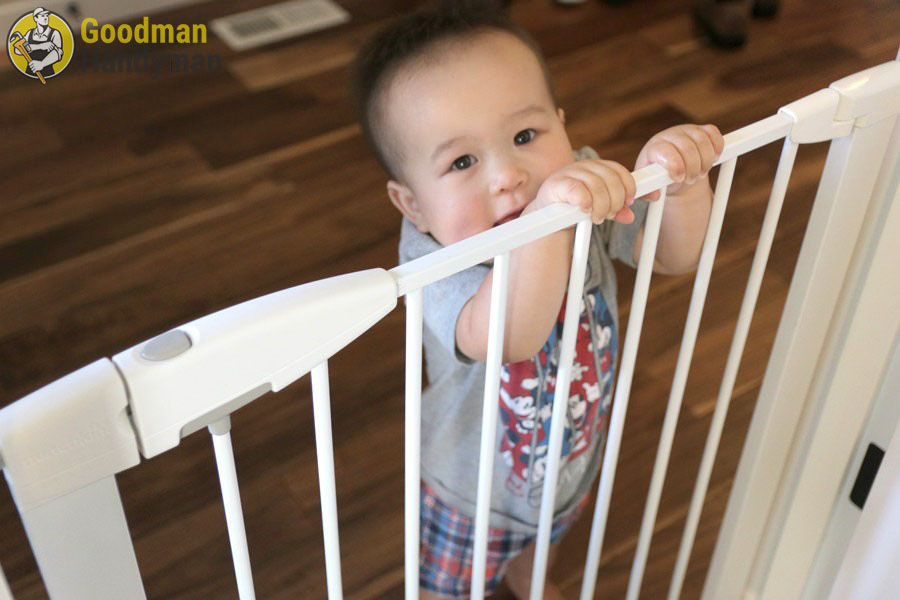 A toddler holding onto a stair gate